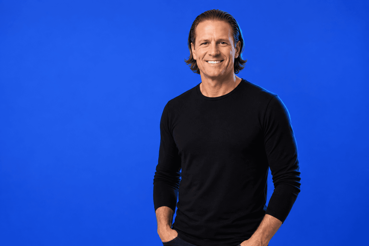 Sevak Girard in a black crewneck against cobalt blue, AI-assisted portrait treatment